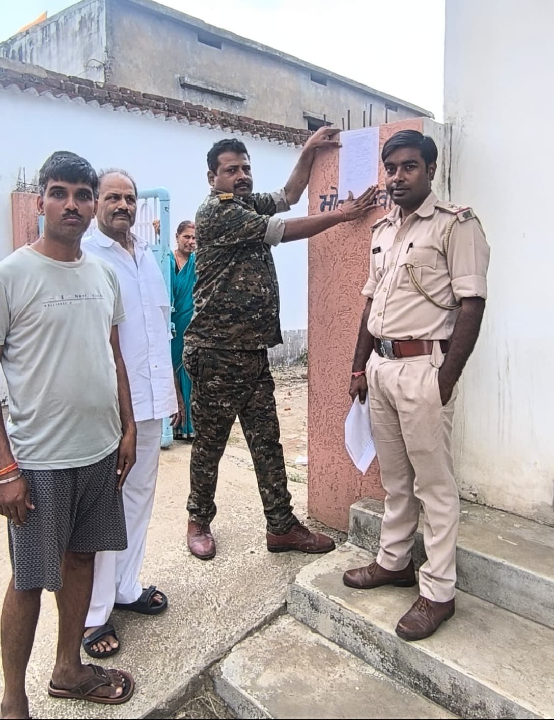 फरार वारंटी के घर कोर्ट के आदेश पर चिपकाया गया इश्तिहार